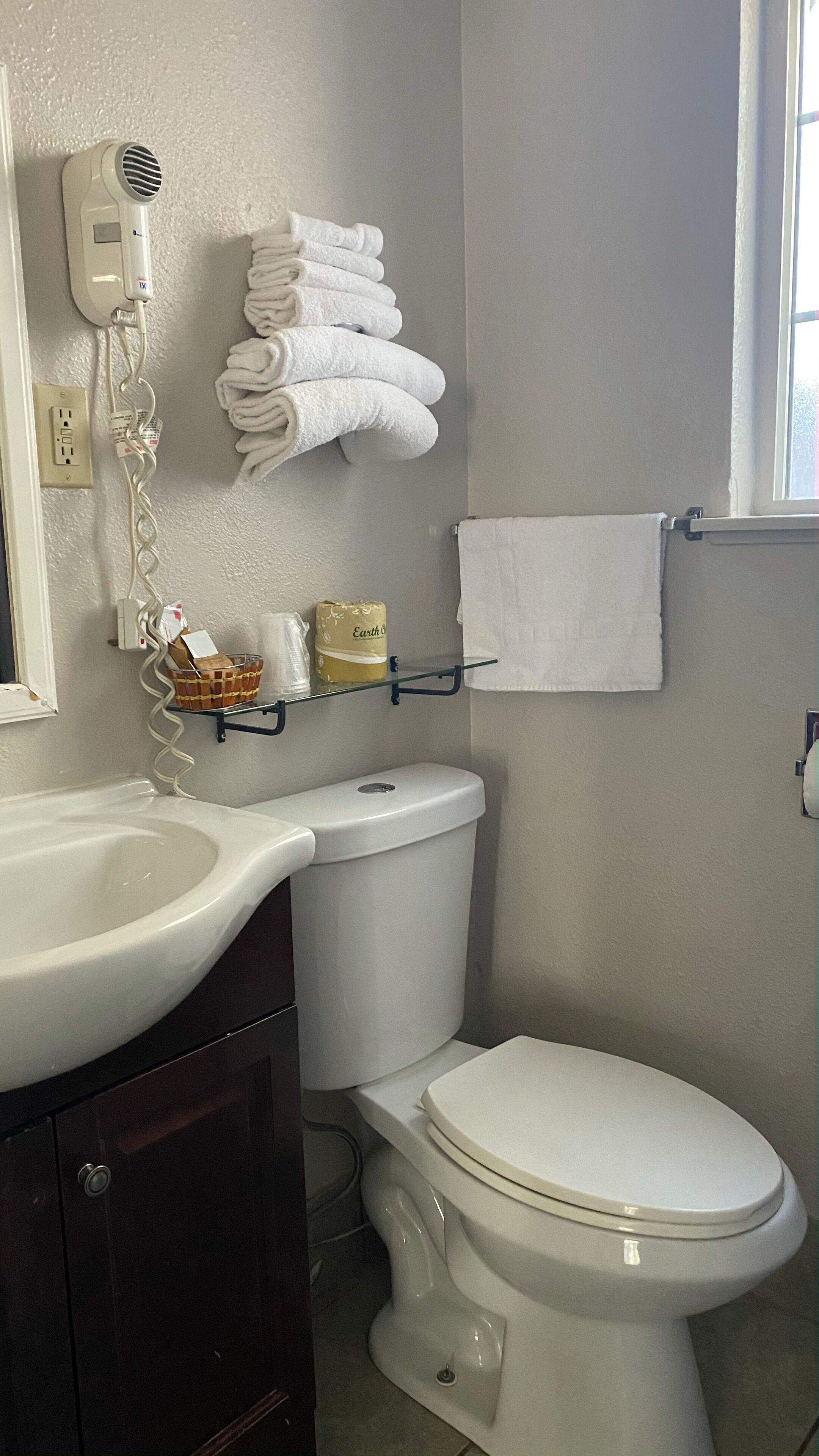 A bathroom with a white sink, a toilet, and a hairdryer mounted on the wall.