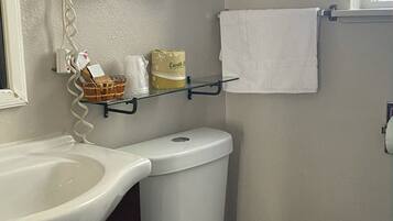 A bathroom with a white sink, a toilet, and a hairdryer mounted on the wall.