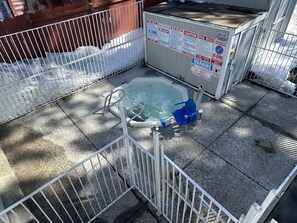 A small indoor pool with a metal fence, surrounded by a concrete floor and a wooden fence.