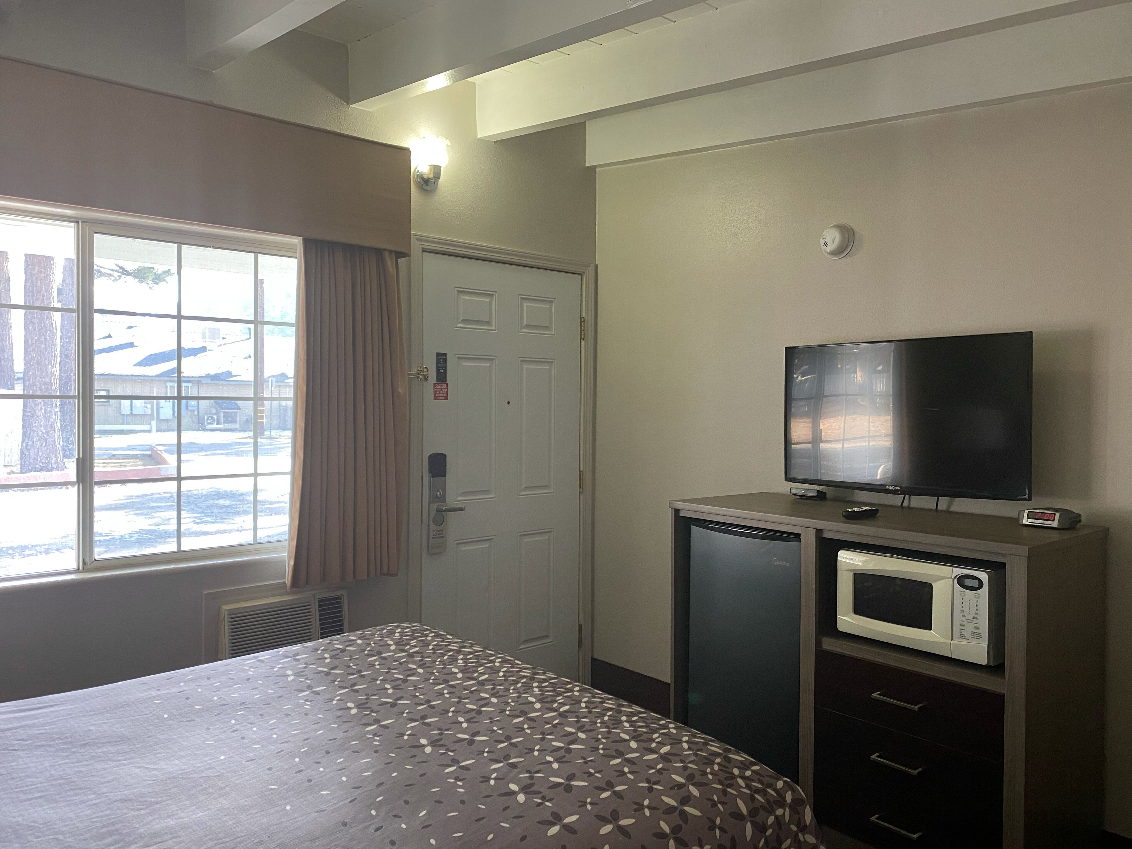 Une chambre d’hôtel équipée d’un lit, d’une télévision, d’un four à micro-ondes et d’une porte dotée d’une serrure de sécurité.