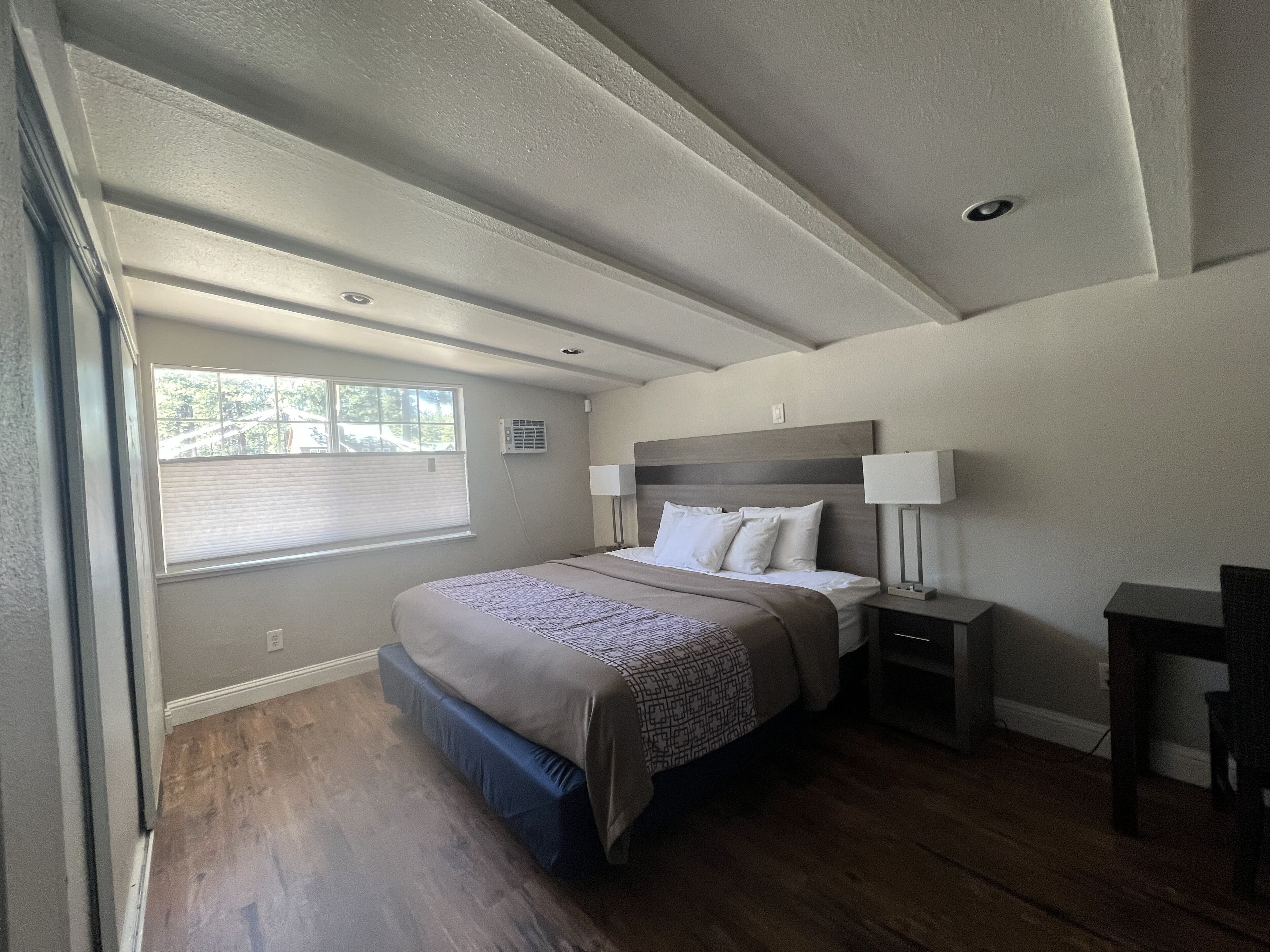 Una camera da letto con un letto grande, lampade sui comodini, una finestra e un soffitto con faretti.