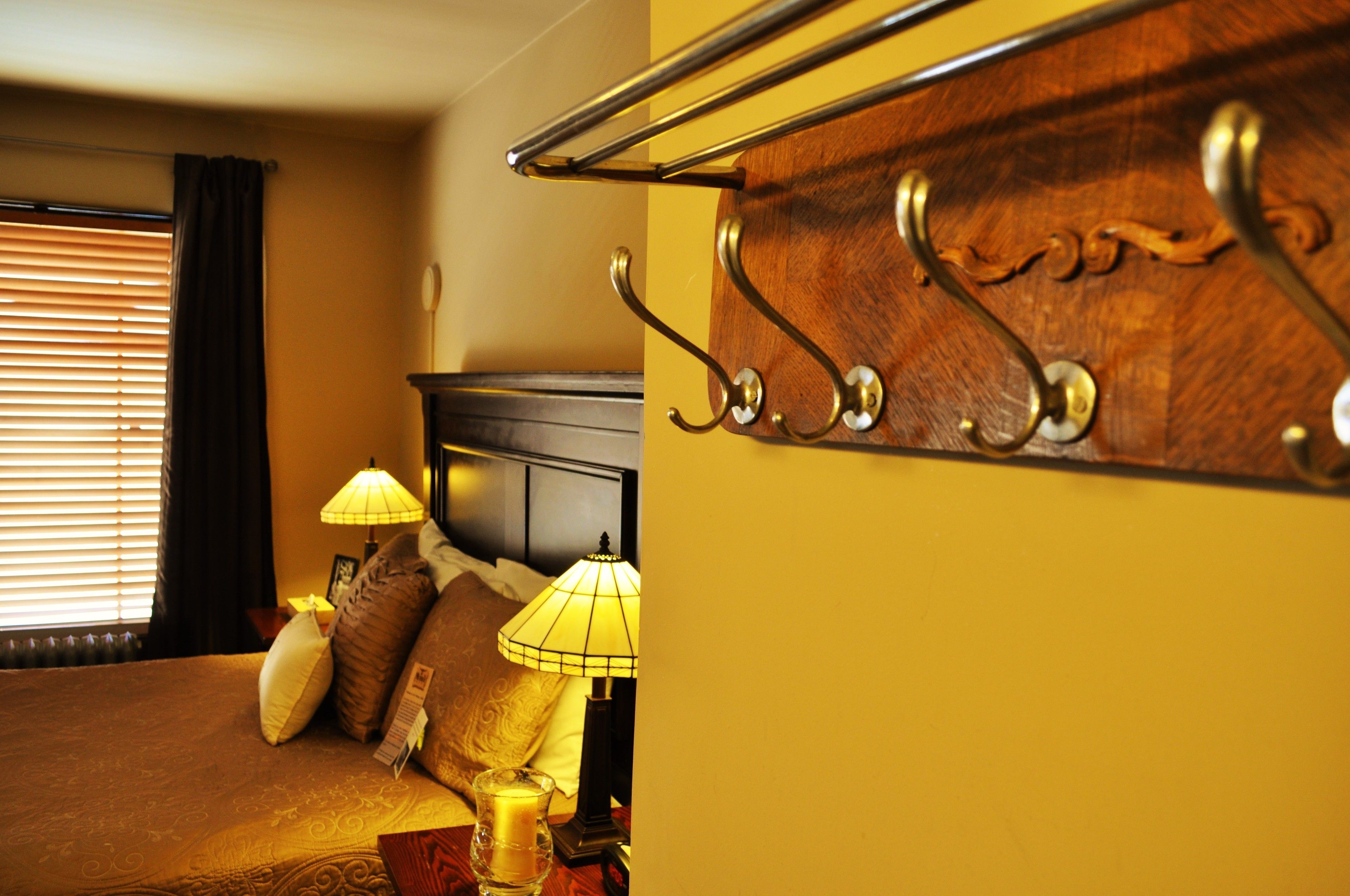 Una habitación de hotel con una cama, dos lámparas de noche, un cabecero de madera y una ventana con persianas.