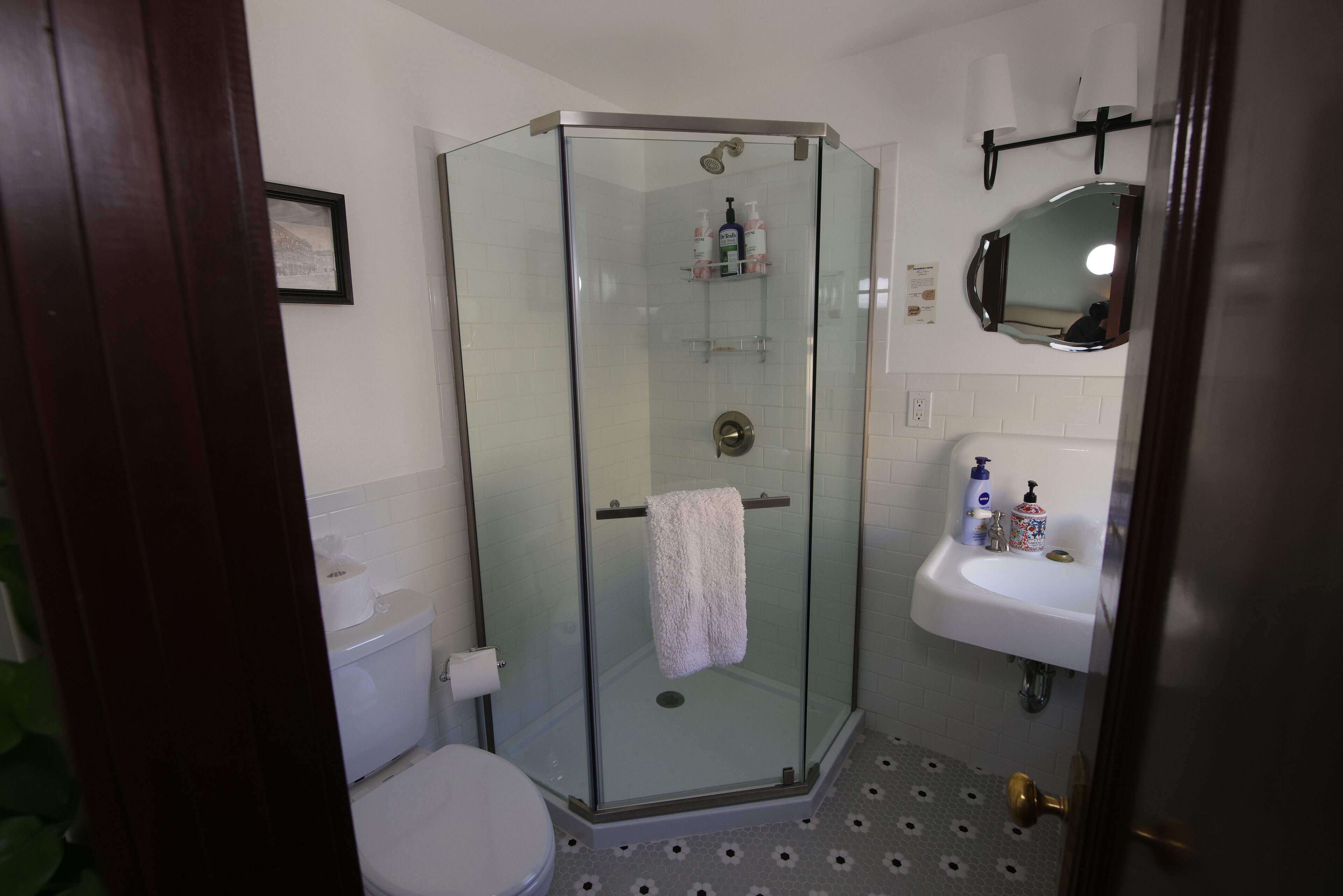 A bathroom with a glass-enclosed shower, a white sink, and a toilet.
