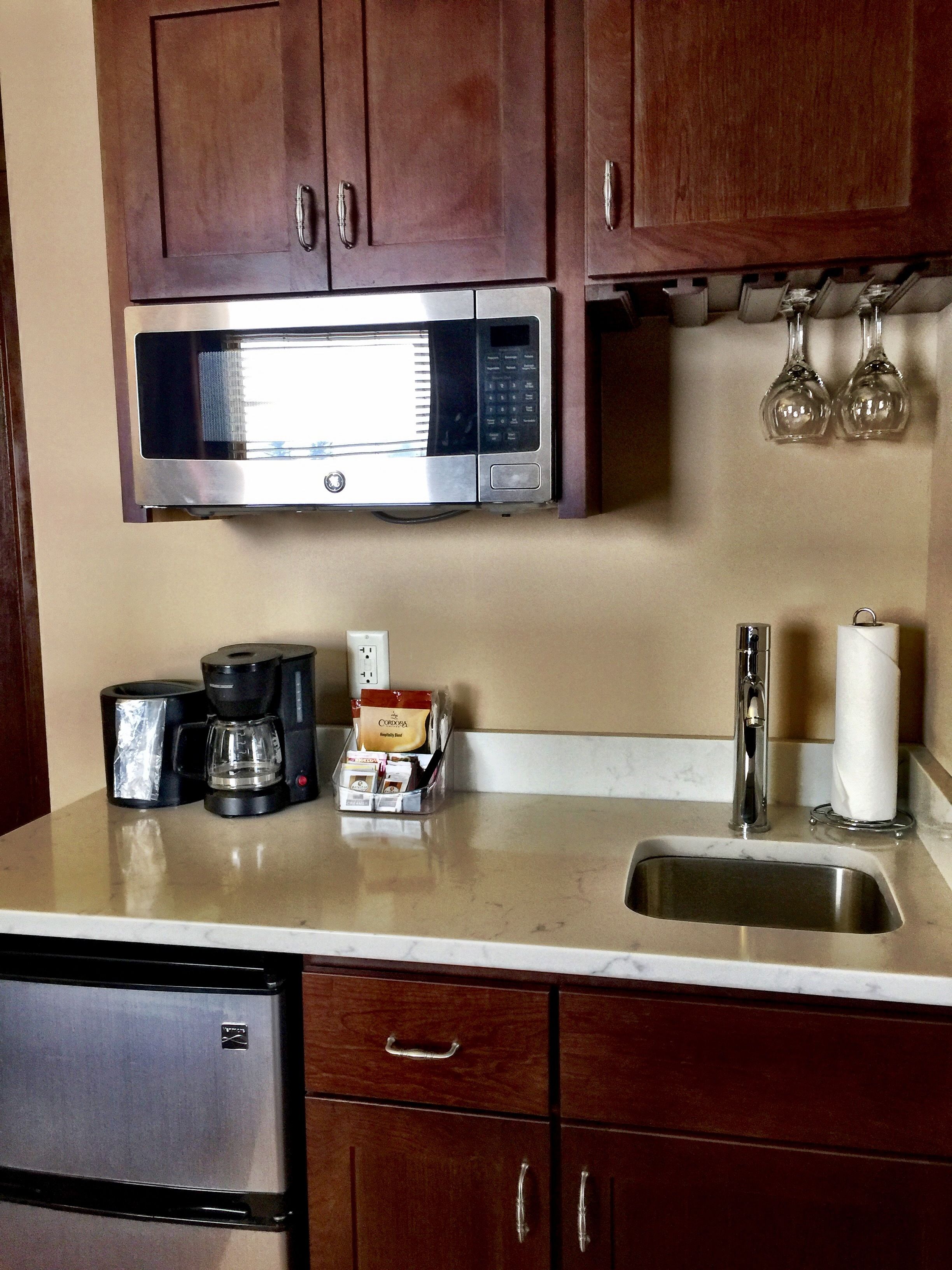 A kitchen with a stainless steel microwave, coffee maker, and a sink.