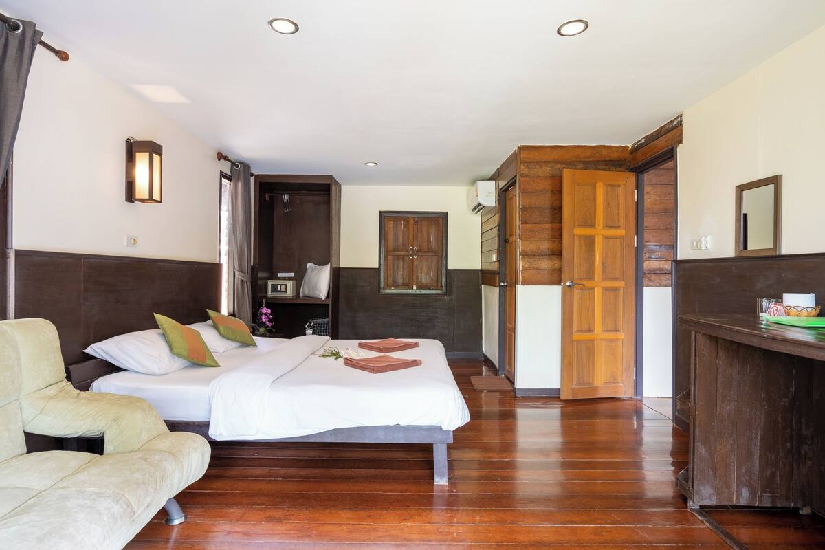 A hotel room with a bed, a sofa, a wooden wardrobe, and a bathroom door.