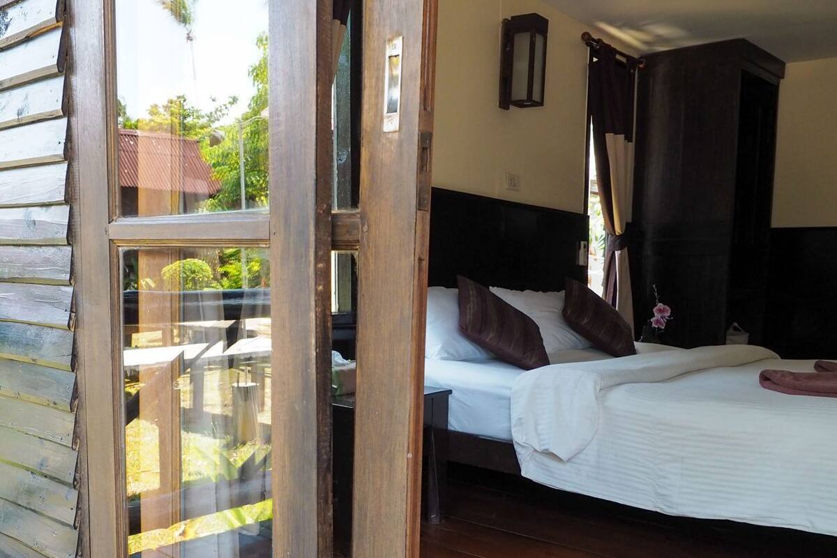 A wooden-framed room with a bed, a nightstand, and a window.