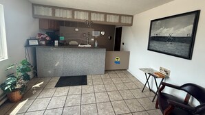 A small, well-lit room with a kitchen area, a dining table, a chair, and a potted plant. - Island Inn (Grand Island)