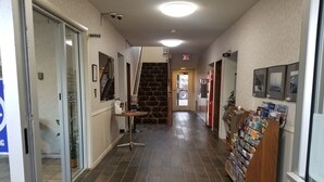 A hallway with a stone wall, a bulletin board, and a travel information kiosk. - Island Inn (Grand Island)