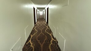 A long, narrow hallway with patterned carpet and white walls. - Island Inn (Grand Island)