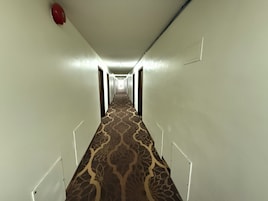 A long, narrow hallway with patterned carpet and white walls.