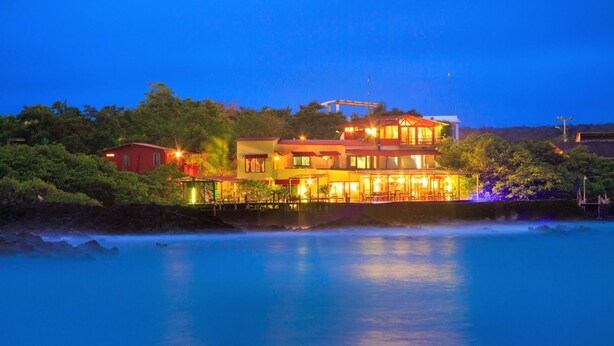 A large, multi-story building with a prominent balcony area, situated near a body of water.