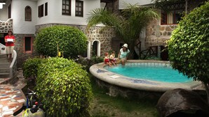 A pool area with a stone wall, a diving board, and a snorkel.