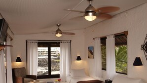 A spacious bedroom with a large bed, two bedside tables, a chair, and a window with curtains.