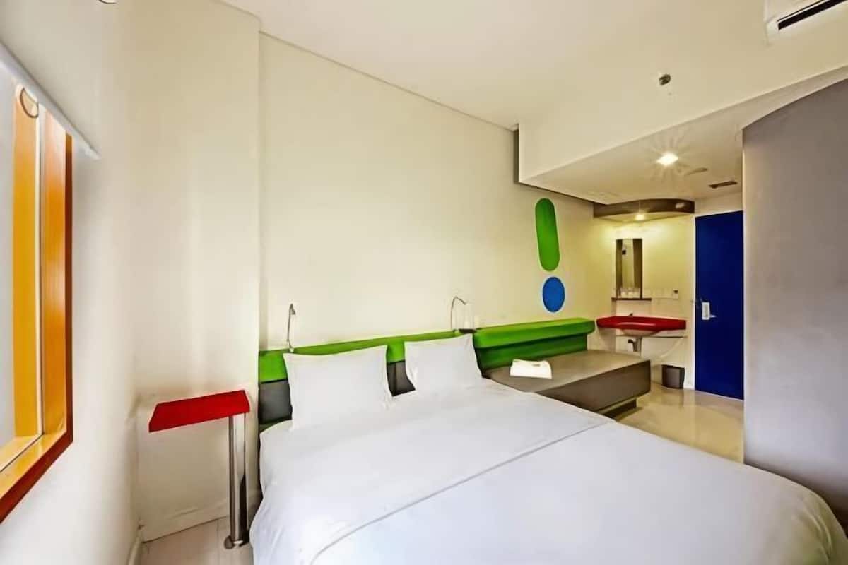 Ein Hotelzimmer mit Bett, Schreibtisch, Stuhl, Spiegel und einem Badezimmer mit Waschbecken und Toilette.