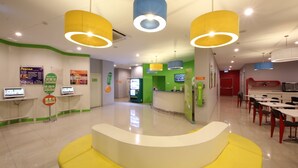 A brightly lit reception area with a central counter, multiple computer stations, and a seating area with yellow cushions.