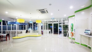 A spacious lobby with a curved seating area, a reception desk, and a digital information kiosk.