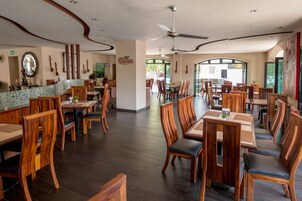 A spacious restaurant with wooden furniture and a modern ceiling fan.