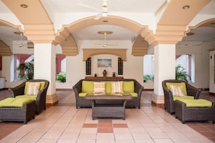 A spacious lobby with a central sofa set, two armchairs, and a coffee table.