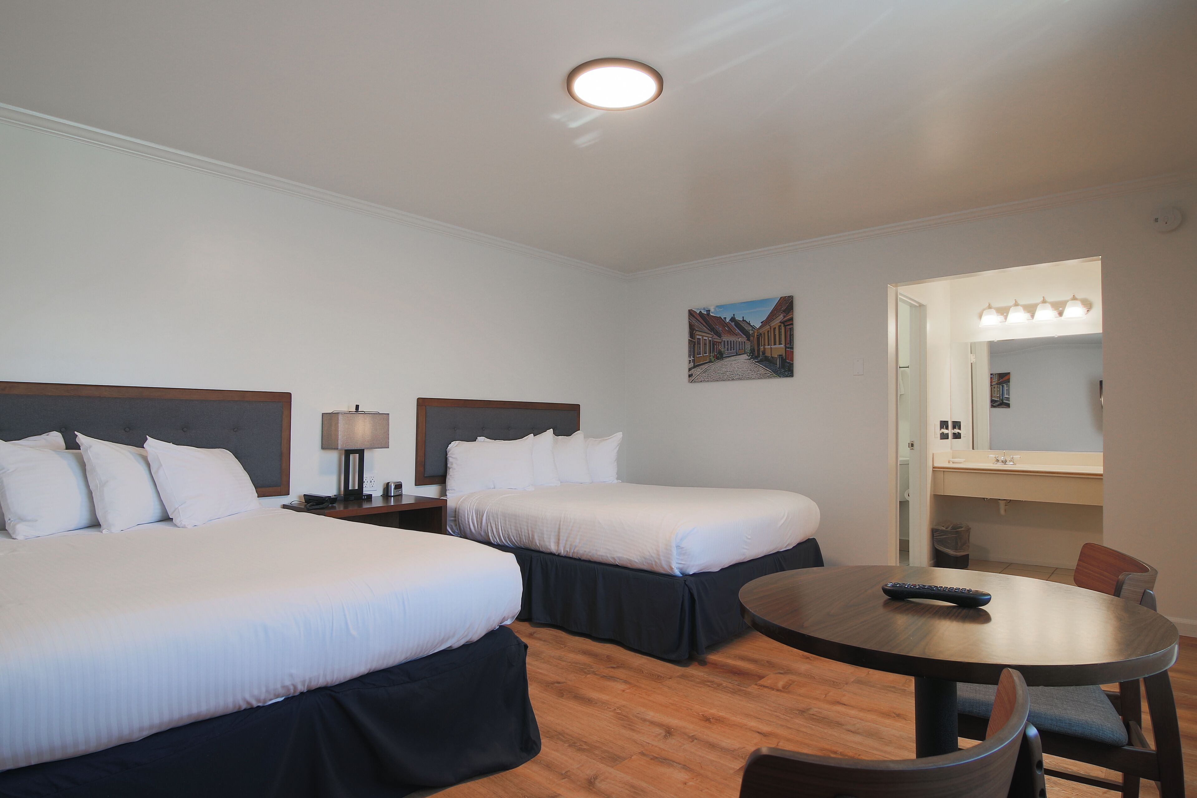 Una habitación de hotel con dos camas, una mesa redonda y un pequeño rincón de descanso.