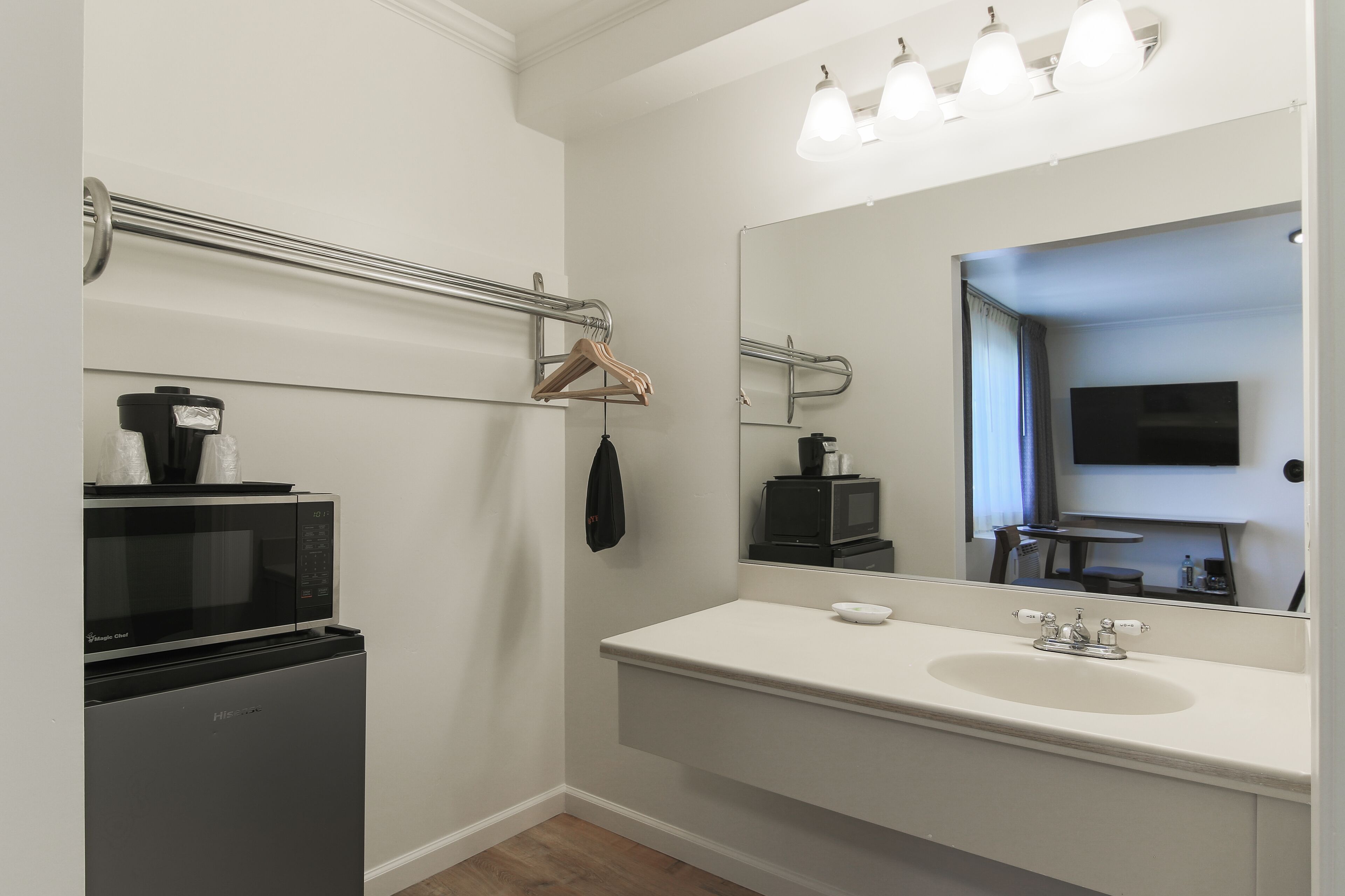 Une salle de bain moderne avec un lavabo blanc, un miroir, un porte-serviettes et un four à micro-ondes.