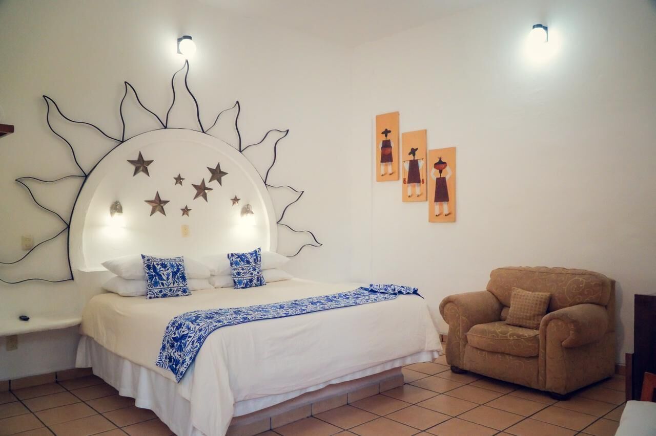 A bedroom with a bed, a nightstand, a chair, and wall art.