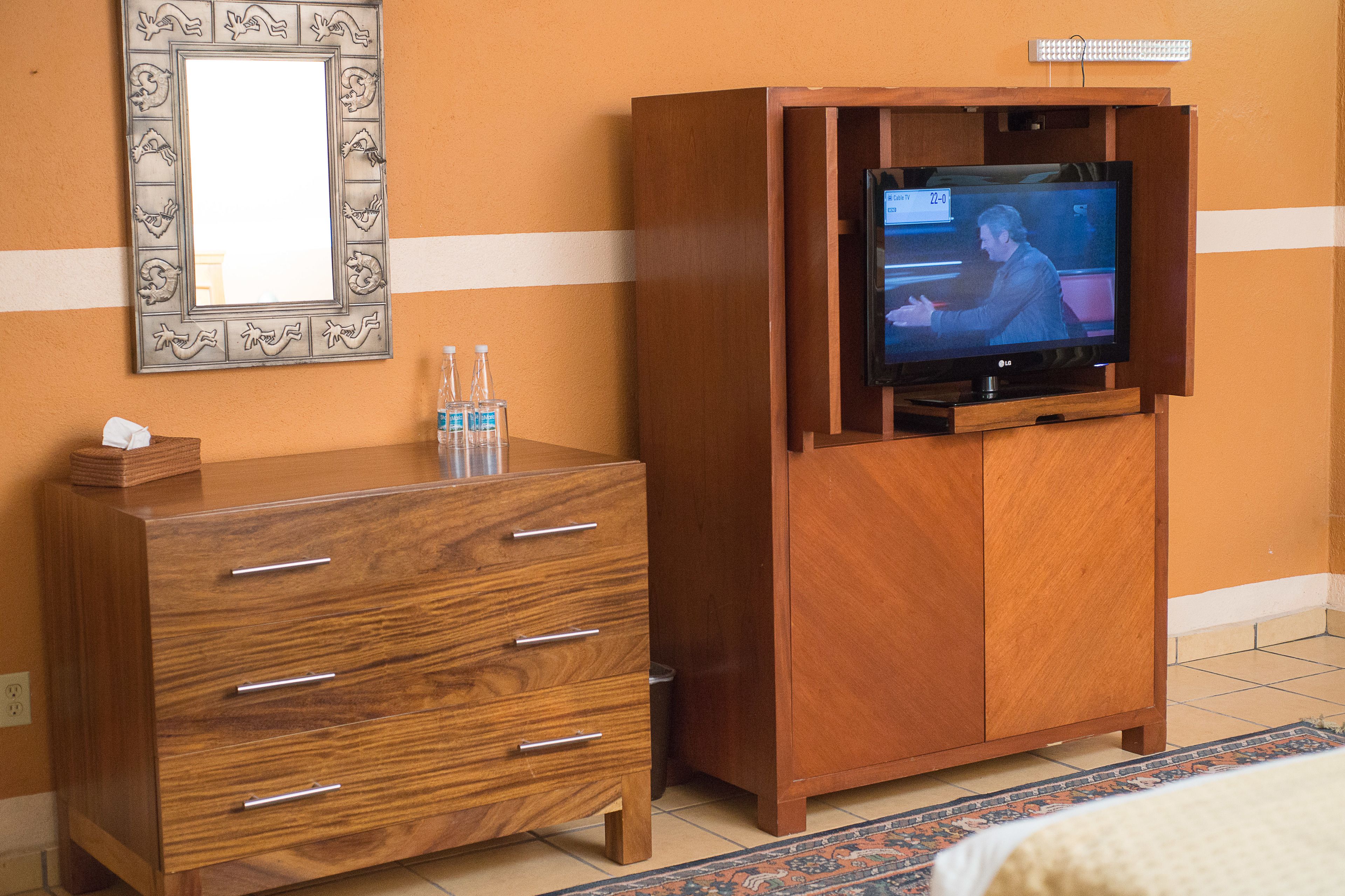 Un aparador de madera con un espejo y un televisor encima.