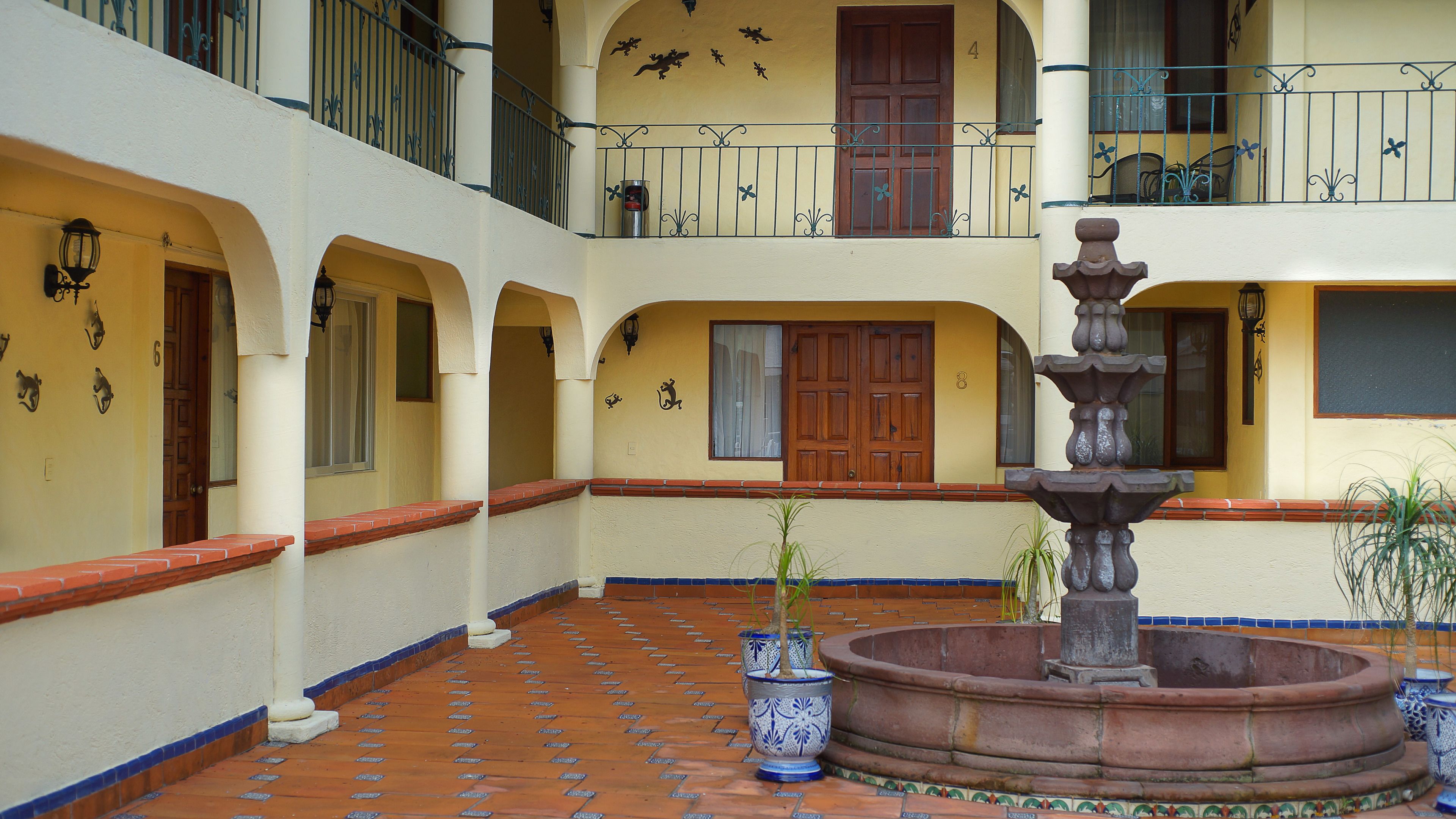 Ein Innenhof mit Brunnen, Blumentöpfen und gefliestem Boden.