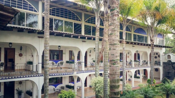 A multi-story building with a courtyard, featuring balconies, arches, and potted plants. - Hotel El Rebozo (Valle de Bravo)