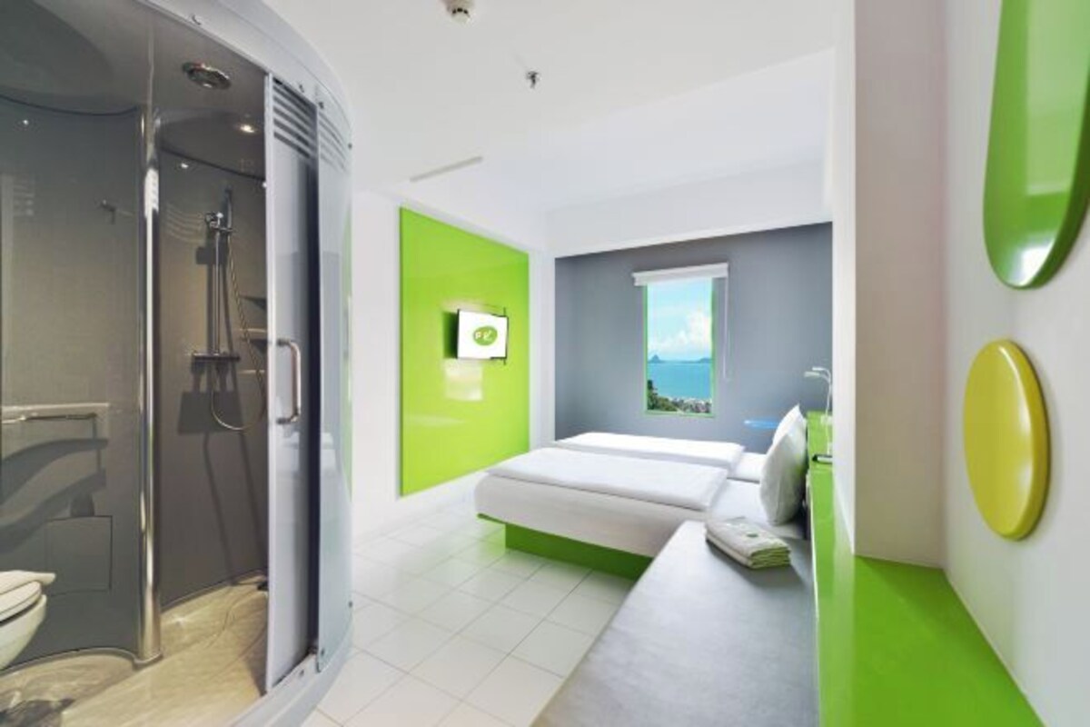 Une salle de bain moderne avec une douche, des toilettes et un mur d’accent de couleur verte.