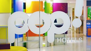 L’entrée d’un hôtel, avec un intérieur aux couleurs vives et l’enseigne « pop! HOTELS » bien visible.