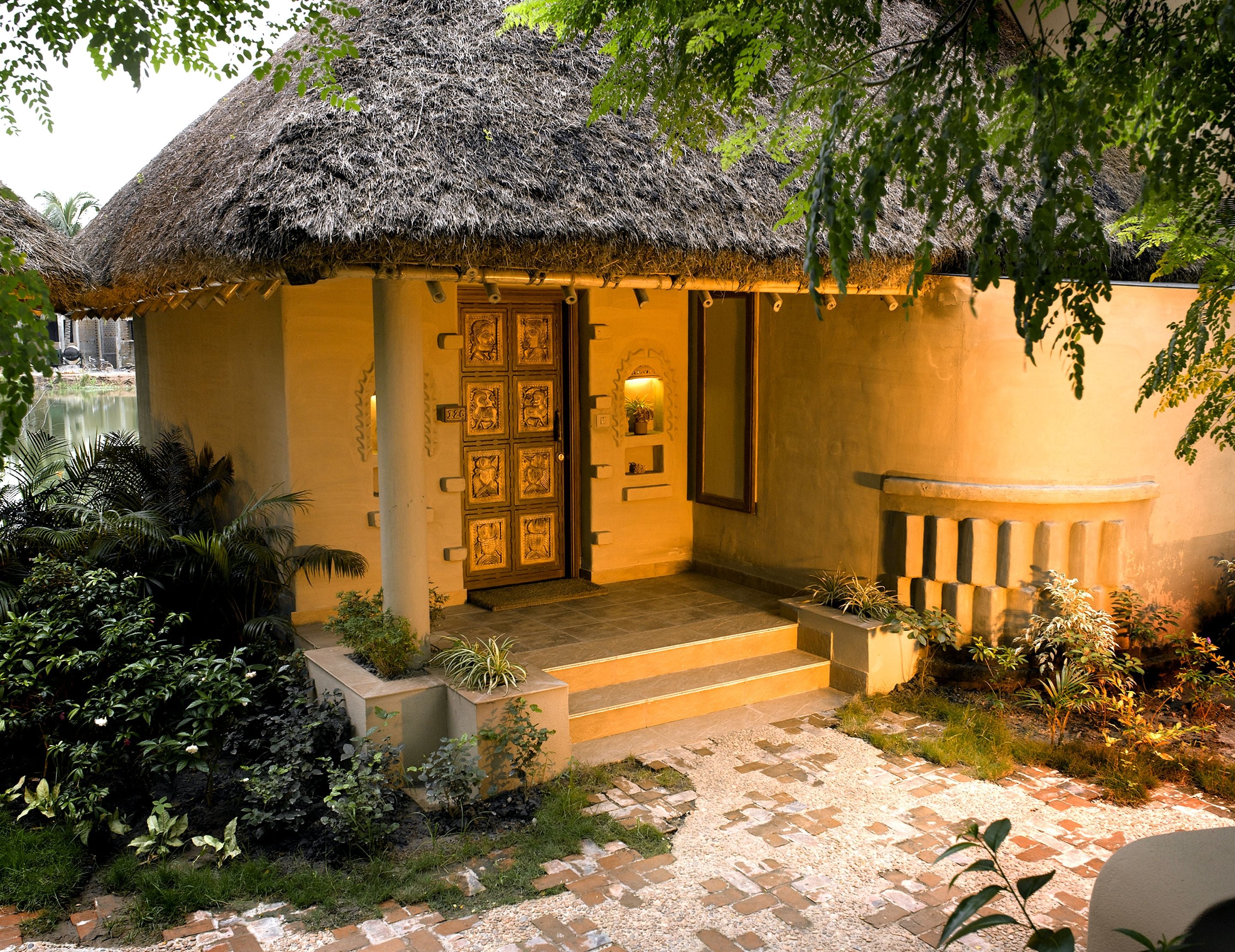 A thatched-roof building with a wooden door and steps leading to a porch.