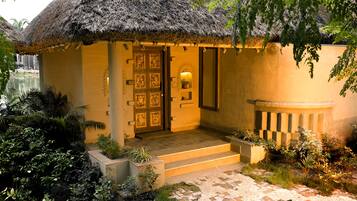 A thatched-roof building with a wooden door and steps leading to a porch.