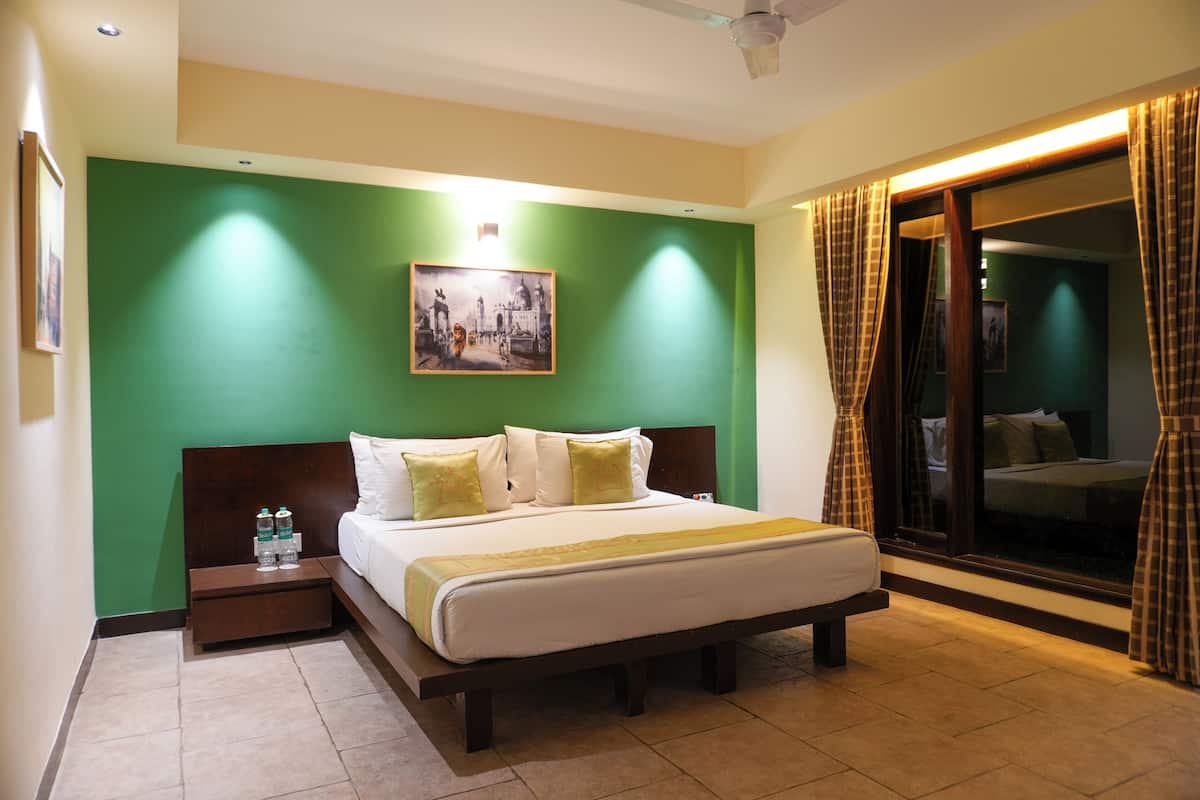 A hotel room with a bed, a nightstand, a painting on the wall, and a view through the window.