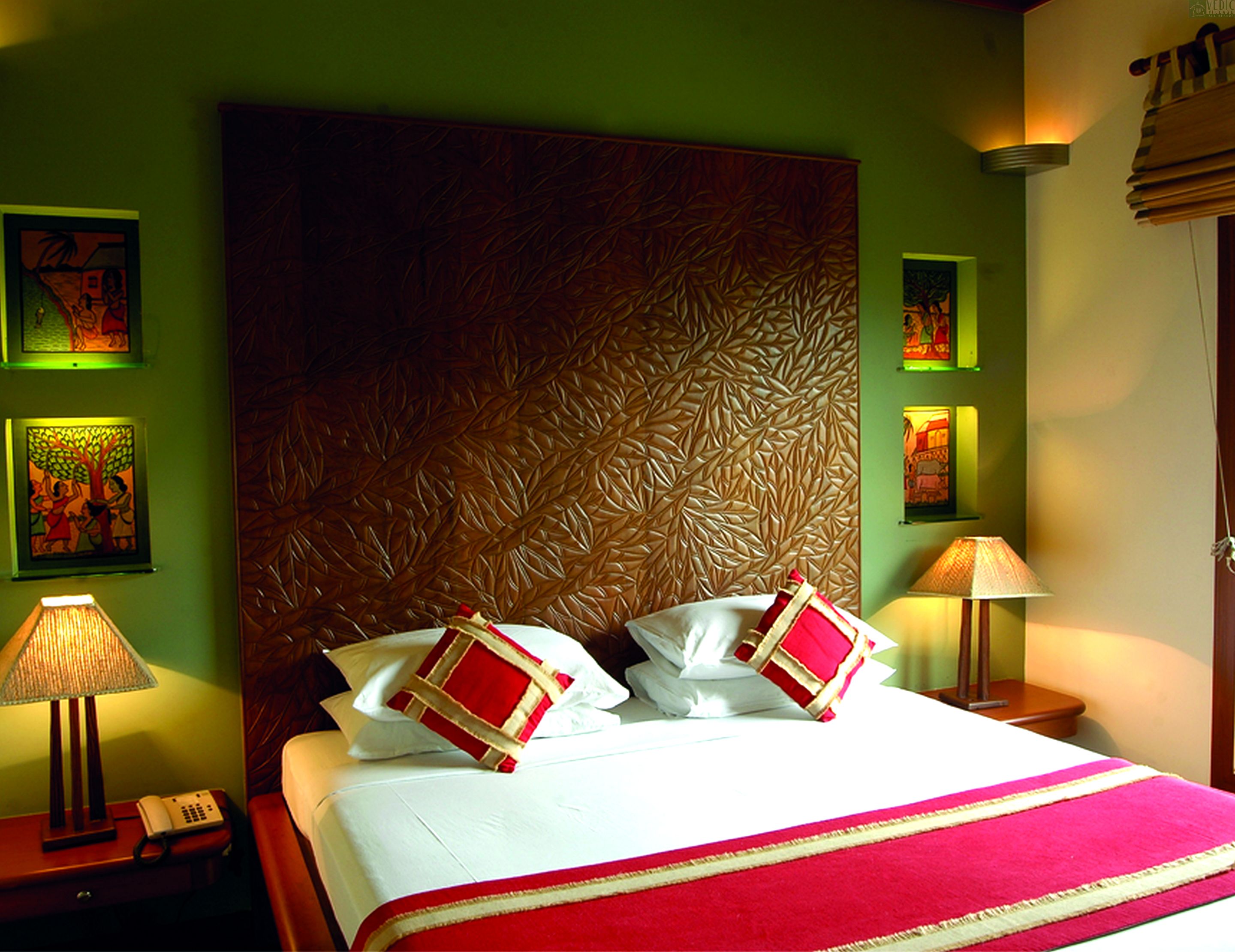 A hotel room with a large bed, a wooden headboard, and artwork on the walls.