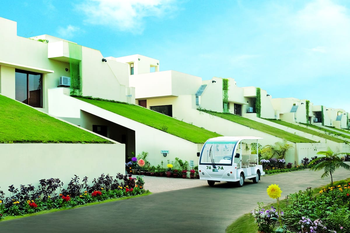 A row of modern, white buildings with green roofs and a white golf cart parked in front.