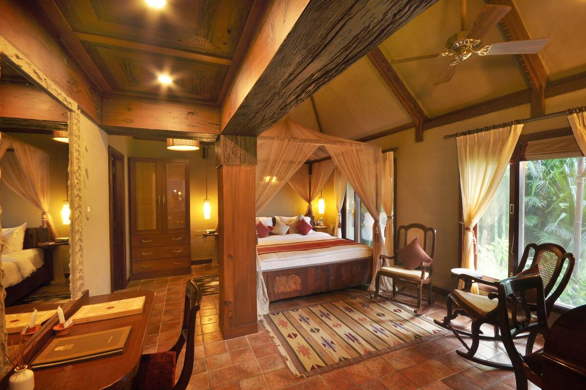 A spacious bedroom with a large bed, a sitting area with chairs, and a view of the outdoors.