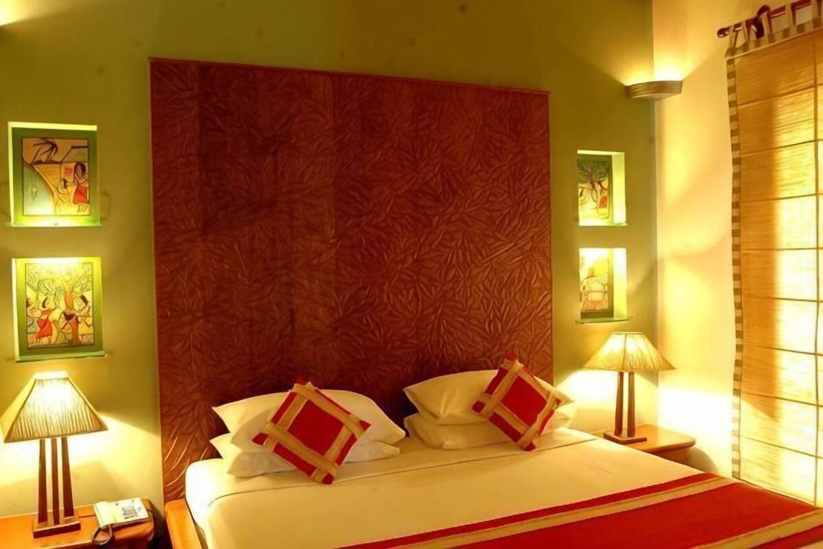 A hotel room with a large bed, a headboard, bedside lamps, and artwork on the walls.