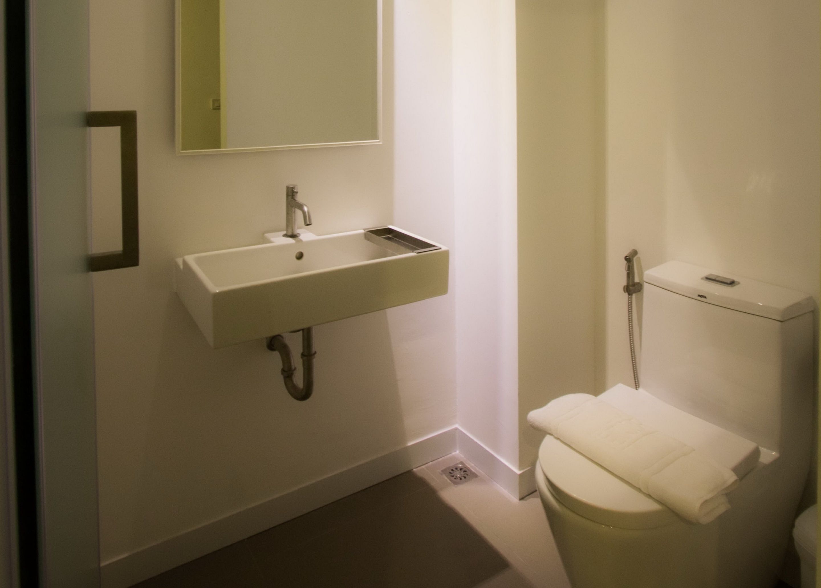 A bathroom with a white sink, mirror, and toilet.