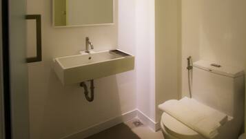 A bathroom with a white sink, mirror, and toilet.