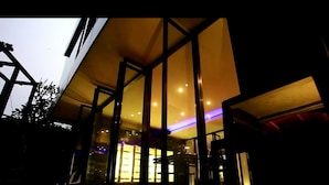 Un bâtiment moderne doté de grandes fenêtres en verre et d’un éclairage intérieur chaleureux.