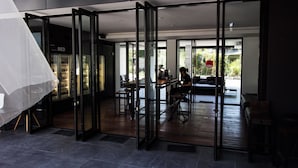 Un intérieur moderne avec une cloison en verre, un coin repas et un espace chambre à coucher visible.