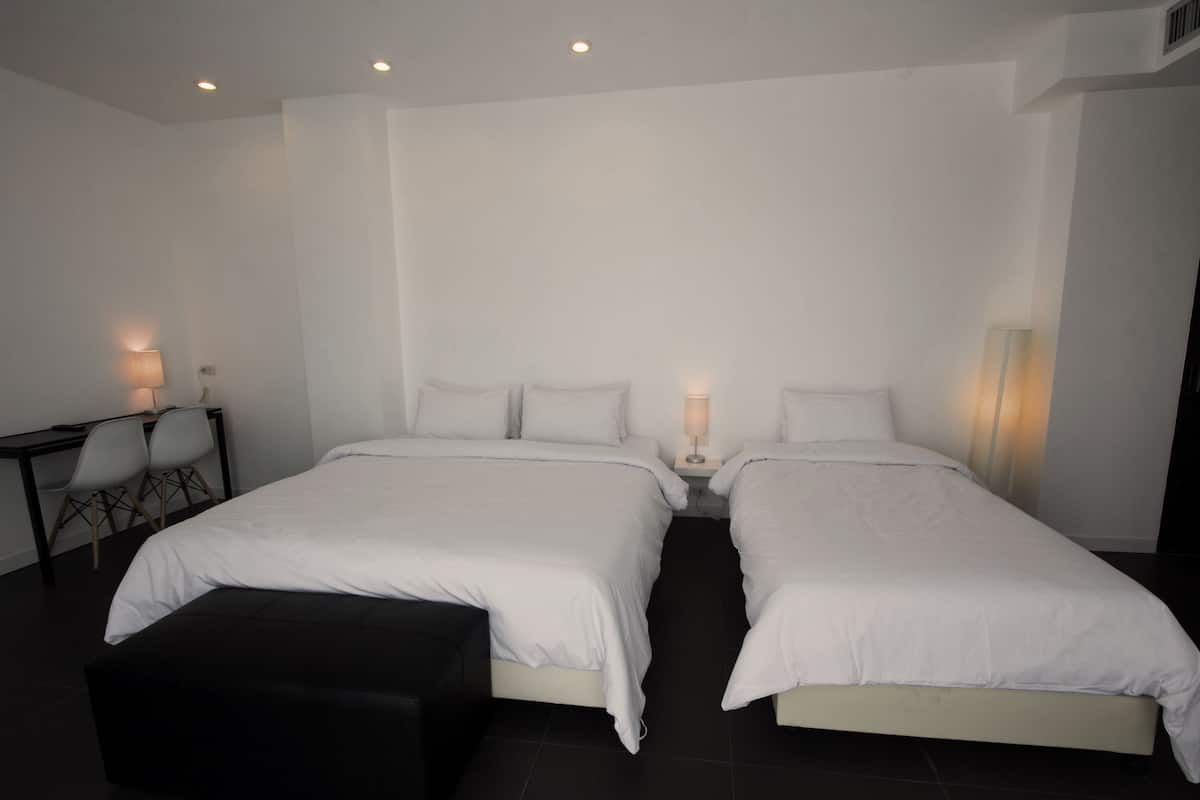 A modern bedroom with two beds, a desk, and chairs.