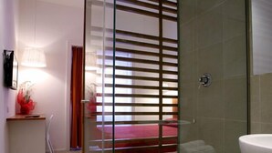 A modern bathroom with a glass partition, a sink, and a shower area. - Why Not Roma (Rome)