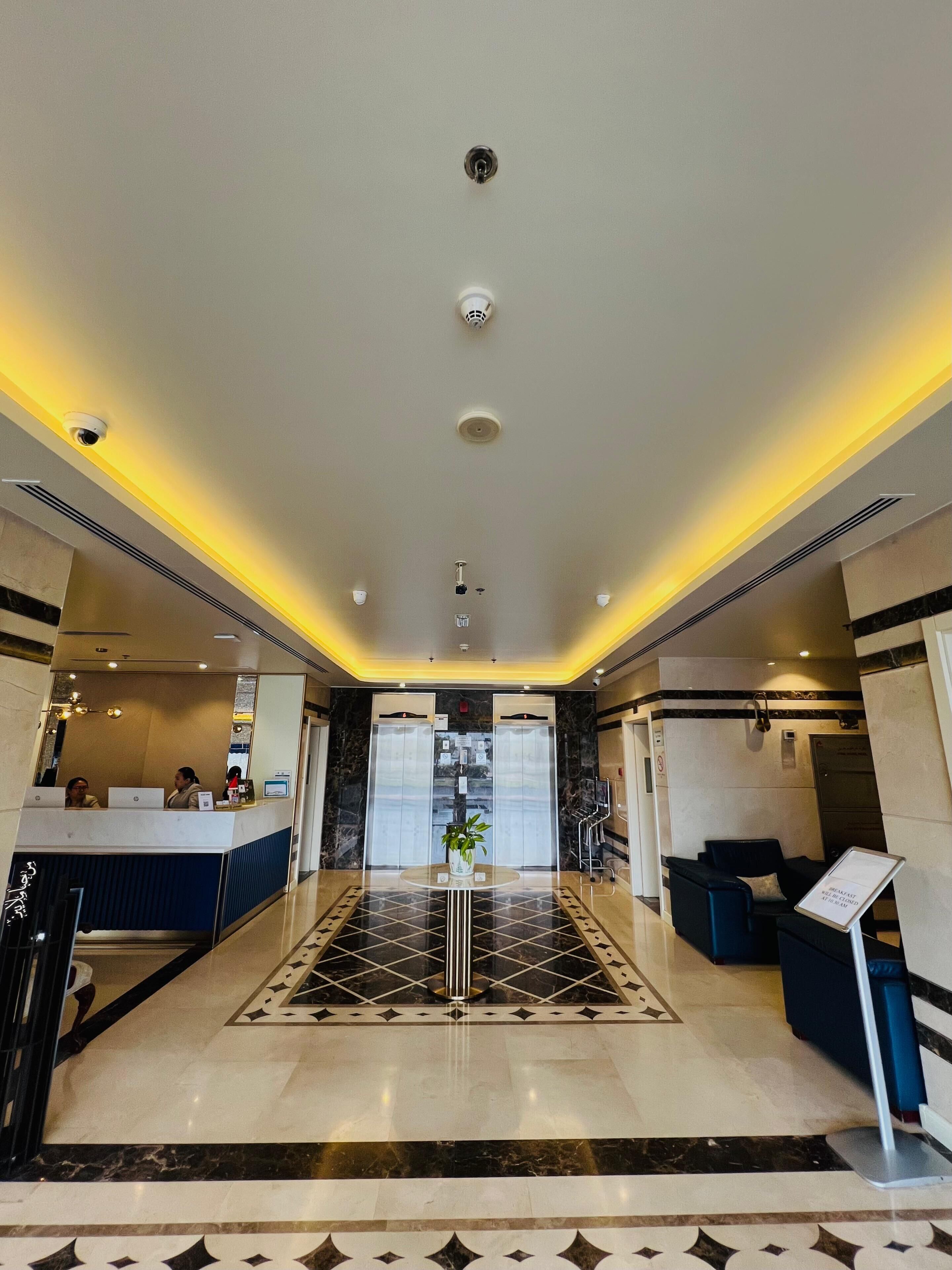 A hotel lobby with a reception desk, seating area, and a check-in counter.