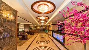 Un vestíbulo de hotel con piso de mármol, un mostrador de recepción y un candelabro.