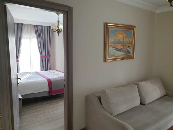 A hotel room with a bed, a sofa, a painting, and a chandelier. - Dab Hotel (Istanbul)