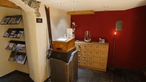 Un vestíbulo con mostrador de recepción de madera, un tablón de anuncios con folletos, una pared roja y una pared de piedra.
