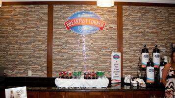 Una zona de desayuno con un letrero que dice "Baymont Breakfast Corner", botellas de bebidas y una mesa con mantel blanco.