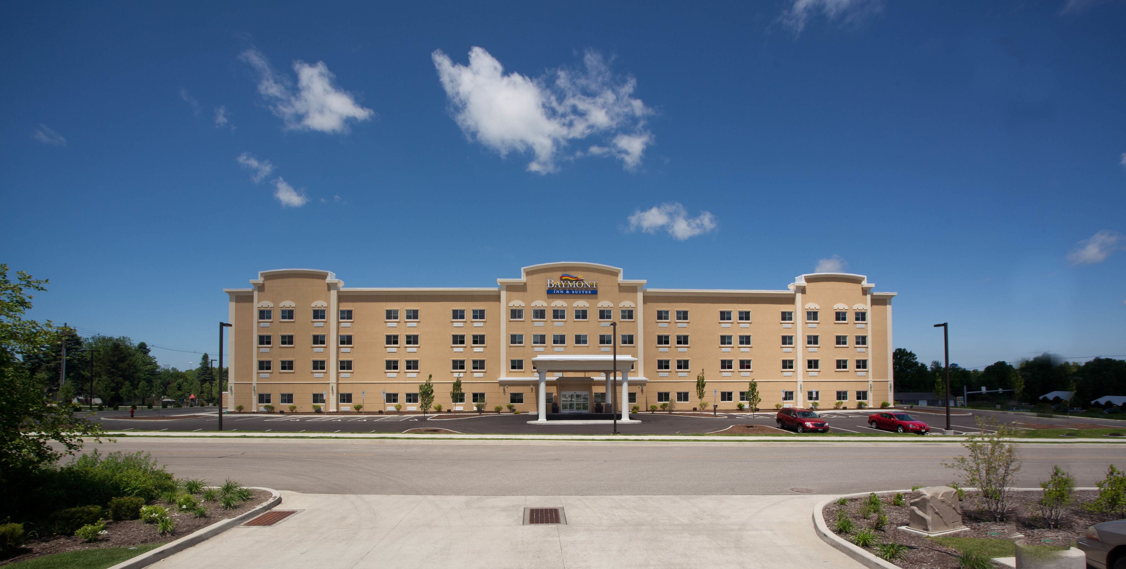 A large, multi-story hotel with a central entrance and a parking lot in front.