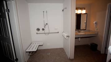 A bathroom with a shower, a hand dryer, a towel rack, and a sink.